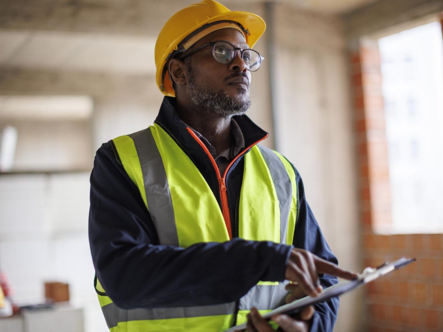 A man wearing a yellow vest and hard hat doing a radon test in the home.