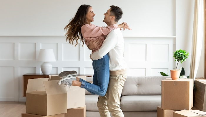 Overjoyed husband swings happy wife, excited to move in new home together.