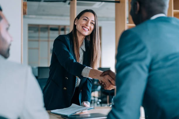 Real estate agent woman shakes hands with man facing away from camera