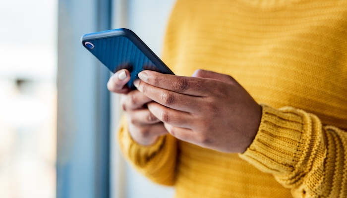 Photo of an unrecognizable woman using a mobile phone indoors.